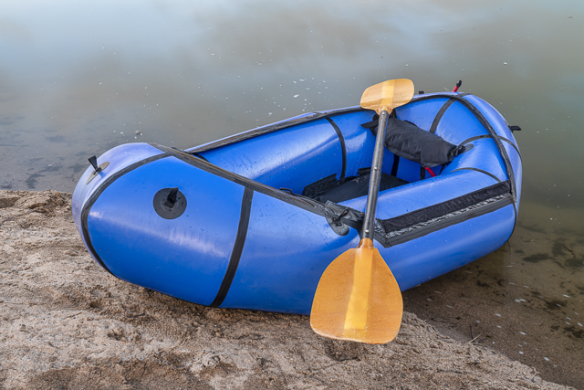 inflatable packraft with paddle on a lake shore