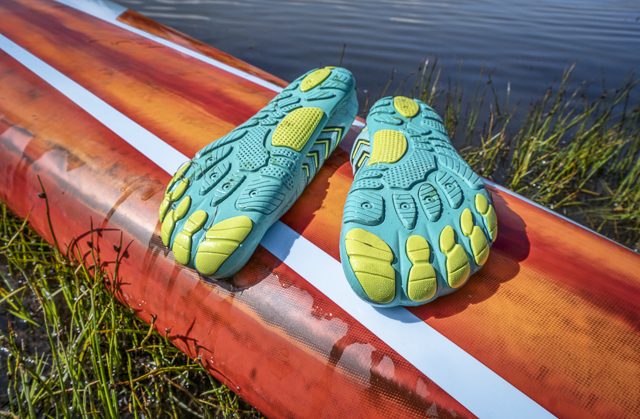 ightweight low-profile water shoes (soles up) for kayaking and other wet sports on a deck of a stand up paddleboard