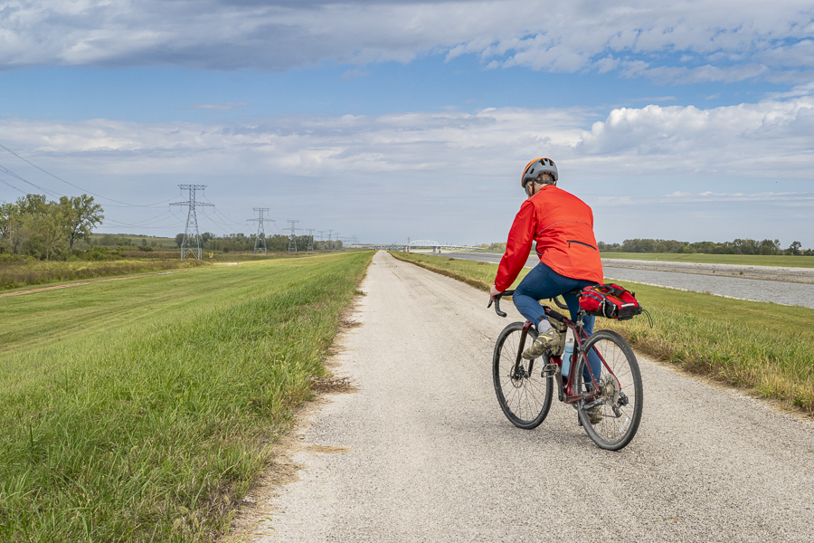 male cyclist is riding a gravel touring bike - biking on a levee trail 