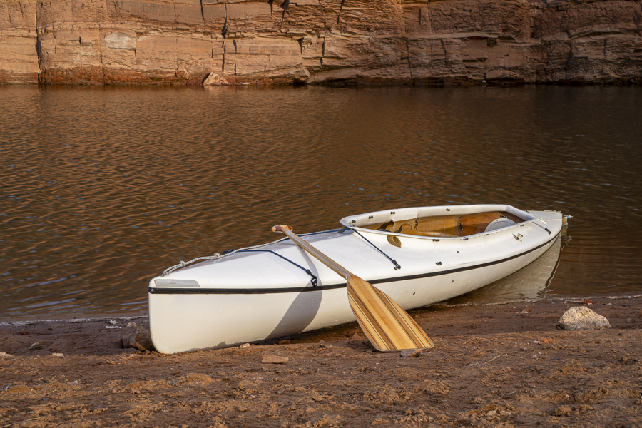 decked expedition canoe with a wooden paddle on a shore of Horsetooth Reservoir in northern Colorado in cold season scenery