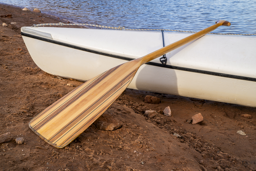 decked expedition canoe with a wooden paddle on a shore of Horsetooth Reservoir in northern Colorado