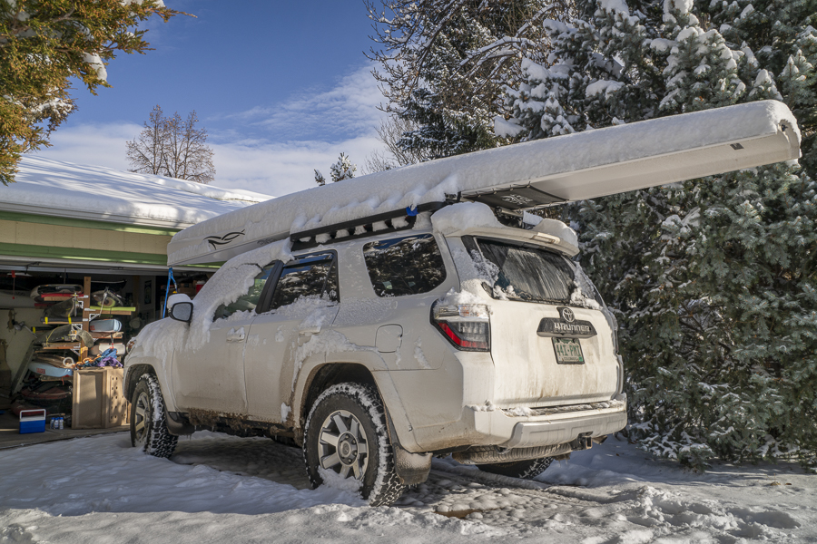 Fort Collins, CO, USA - November 25, 2023: Toyota 4runner SUV with a rowing shell, LiteRace 1x by Liteboat on roof racks covered by snow in a driveway.