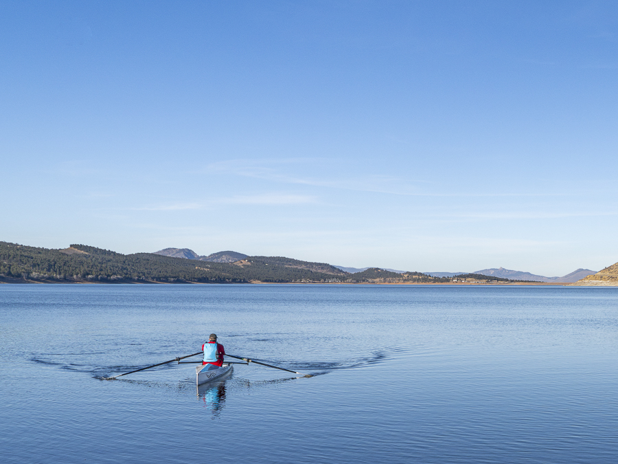 Lonely rower in a coastal rowing shell - Carter Lake in fall or winter scenery in northern Colorado.